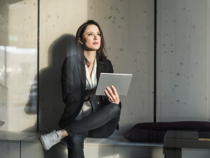 GeschÃ¤ftsfrau mit Tablet sitzt im Loungebereich im BÃ¼ro.