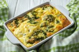 Kartoffel-Brokkoli-Gratin ohne Vorkochen in einer Auflaufform, darum ist ein grÃ¼n-weiÃŸ kariertes Geschirrtuch drapiert.