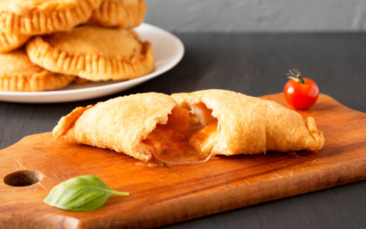 Ein Panzerotti mit Tomate-Mozzarella-FÃ¼llung, der in der Mitte durchgeschnitten wurde.