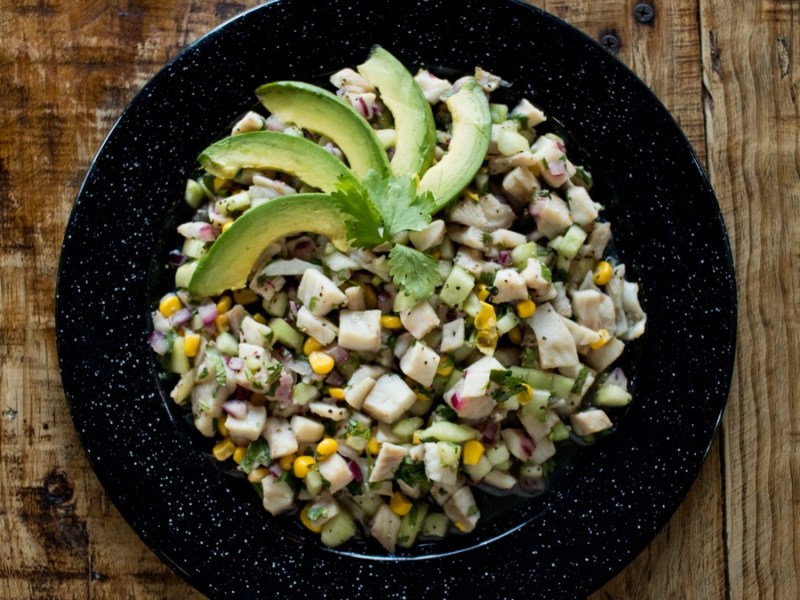 Veganes Ceviche auf schwarzem Teller und braunen Tisch.