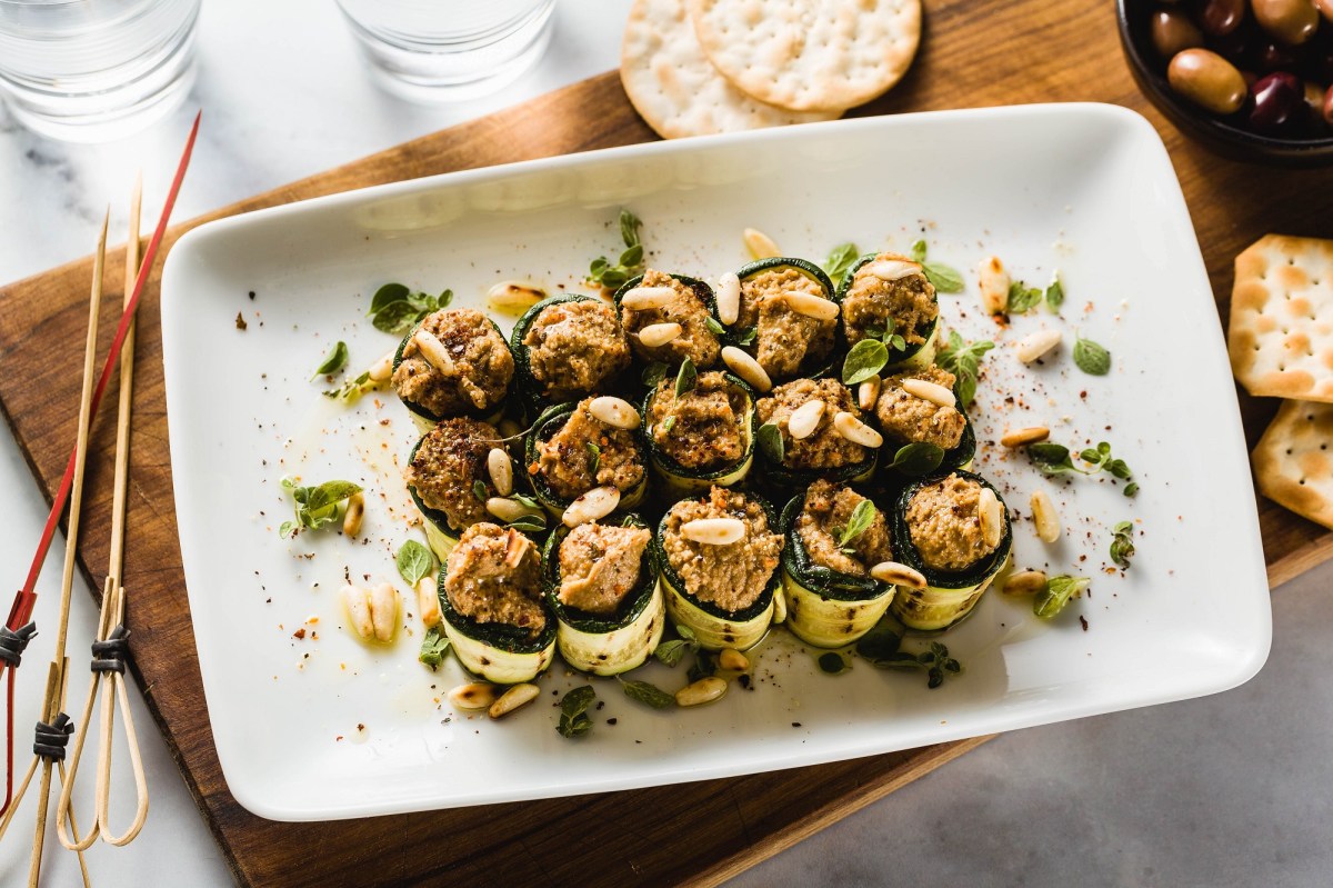 Zucchini-RÃ¶llchen mit Olivencreme auf einem Tablett.