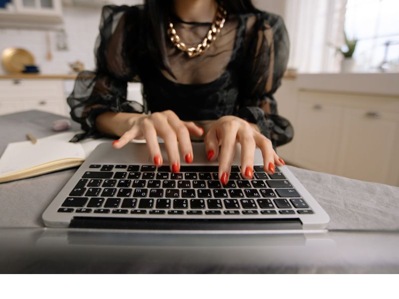 Eine Frau mit roten FingernÃ¤geln tippt auf einer Tastatur.