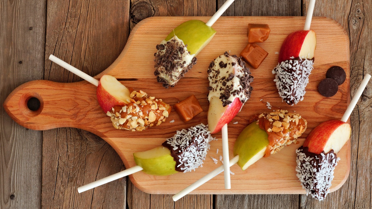 Apfel-Lollies am Stiel mit Schokolade und Toppings.