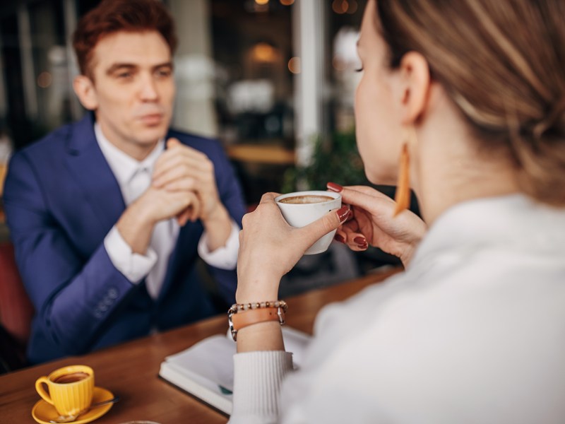 Kaffeetassen-Test: GeschÃ¤ftsmann, der mit einer Frau ein GesprÃ¤ch fÃ¼hrt. Sie trinkt einen Kaffee.