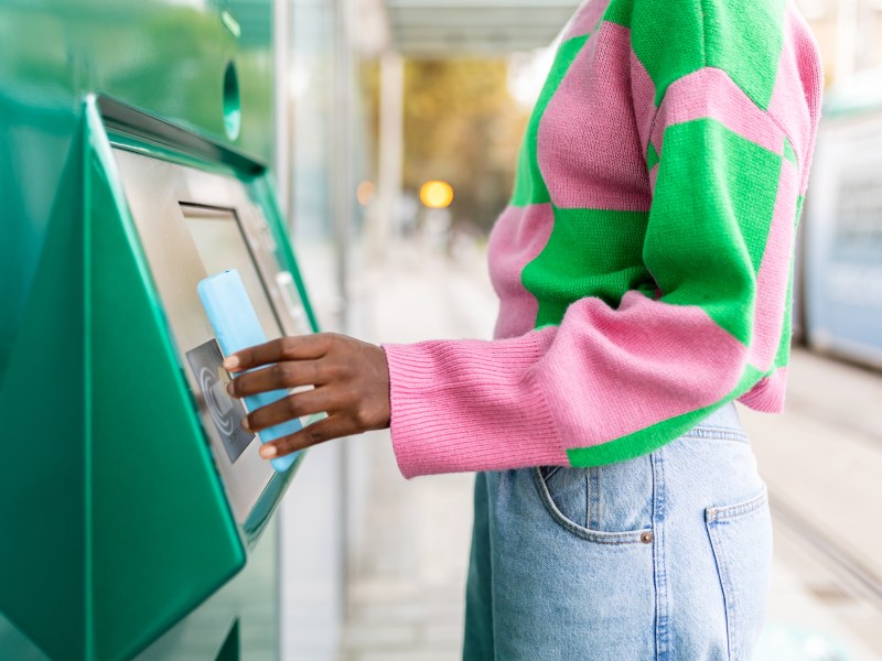 Frau in pink, grÃ¼nen Pullover hebt Geld ab.