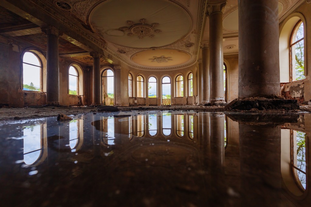 Eine überflutete große Halle mit Säulen in einer alten verlassenen Lost Places, Wasserreflexion.