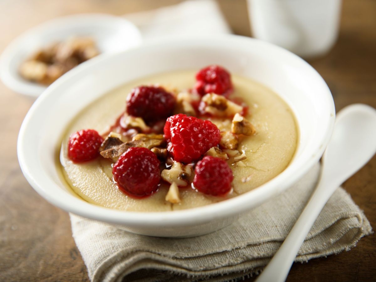 GrieÃŸpudding-Bowl in einer SchÃ¼ssel angerichtet, dekoriert mit frischen Beeren und NÃ¼ssen. Die Schale steht auf einer hellen Stoffserviette und ein weiÃŸer TeelÃ¶ffel liegt daneben.