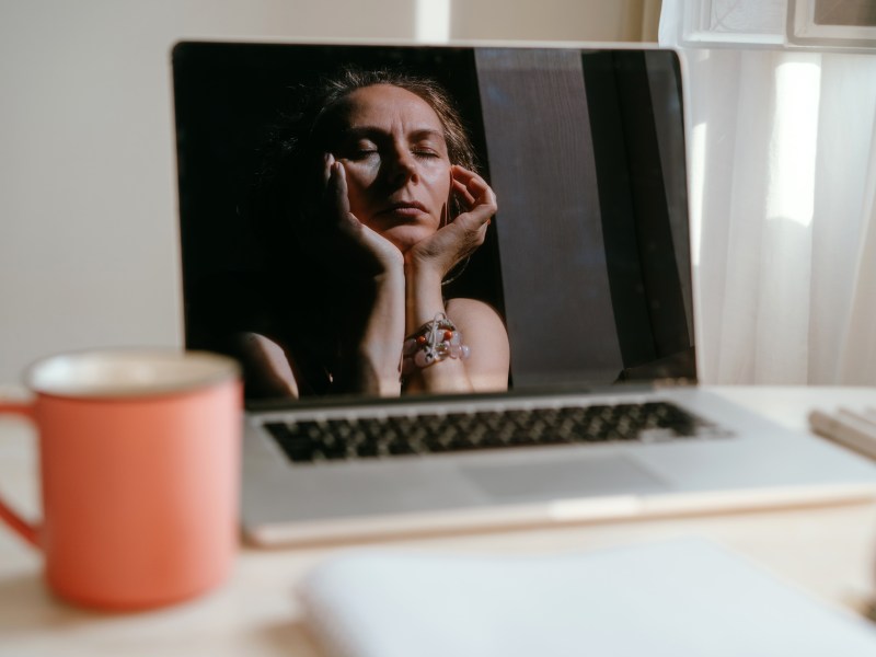 PortrÃ¤t einer Frau, die am Schreibtisch sitz. Hier Spiegelbild spiegelt sich in ihrem Laptop.