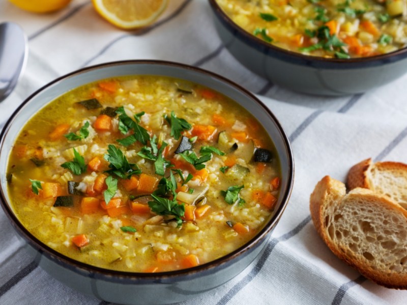 Eine SchÃ¼ssel Reissuppe. Daneben liegen 2 StÃ¼cke Brot.