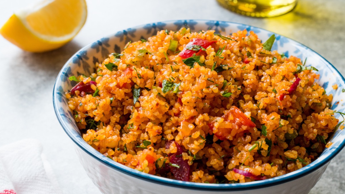 Eine SchÃ¼ssel mit tÃ¼rkischem Bulgursalat. Daneben liegt eine Zitronenspalte.