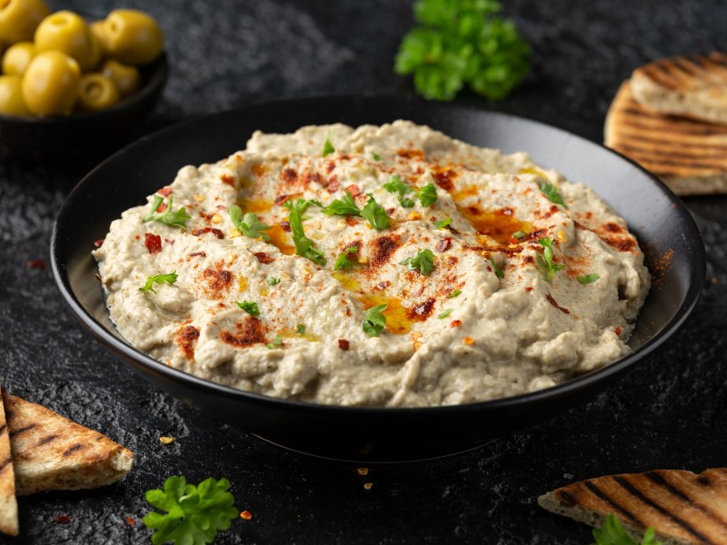 Baba Ganoush in einer schwarzen Schale mit OlivenÃ¶l und Petersilie dekoriert