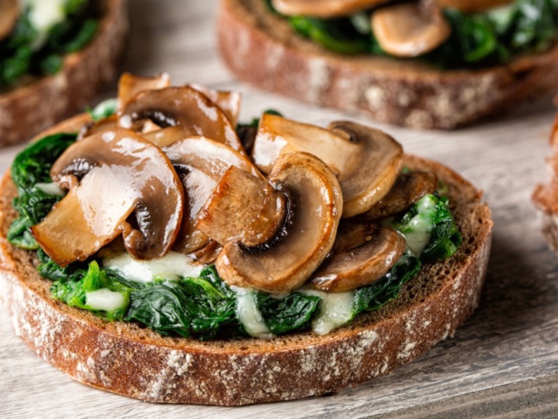 Mehrere Portionen Champignon-Bruschetta mit Ricotta und frischen KrÃ¤utern.