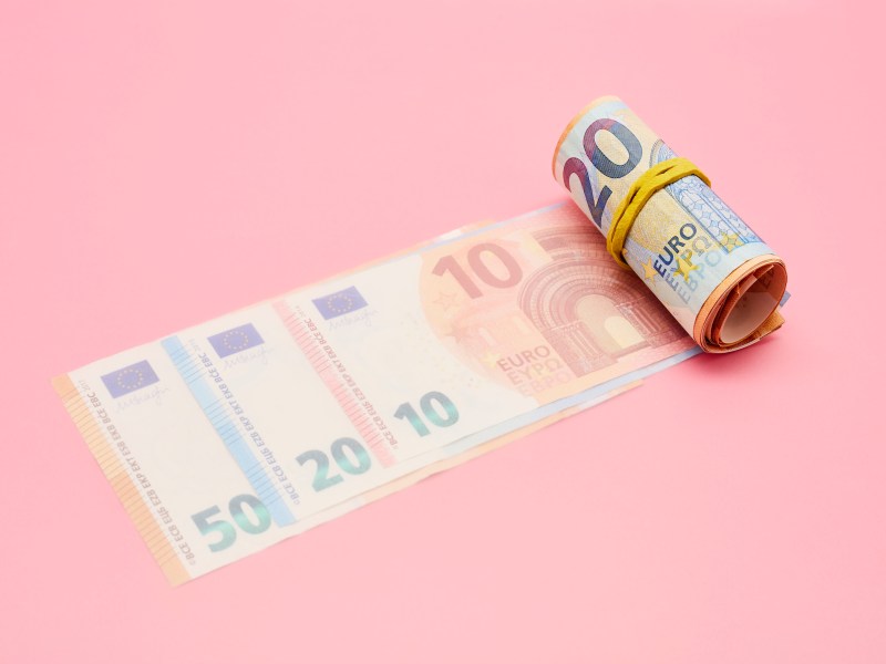 Gehaltsabrechnung: Rolle Euro-Banknoten auf rosa Hintergrund.