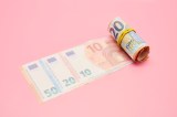 Gehaltsabrechnung: Rolle Euro-Banknoten auf rosa Hintergrund.