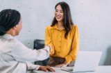 Zwei Frauen schÃ¼tteln sich im BÃ¼ro die Hand.