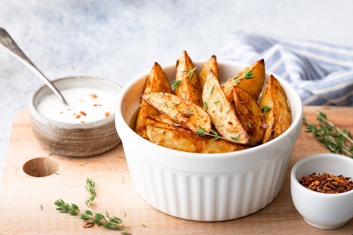 Eine weiÃŸe Schale Kohlrabi-Wedges auf einem Brett, auf dem auch einige weitere SchÃ¼sseln mit Dips stehen.