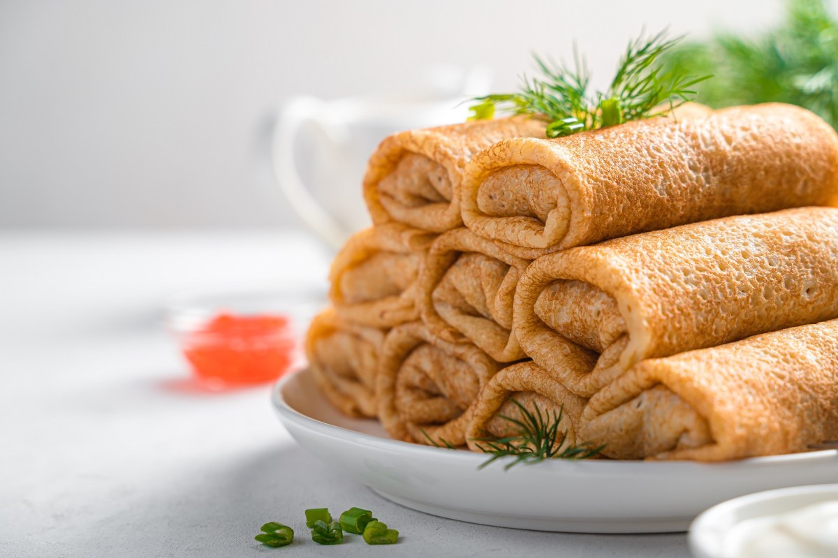 Ein Stapfel Pfannkuchen-FrischkÃ¤se-RÃ¶llchen auf einem Teller, Nahaufnahme.