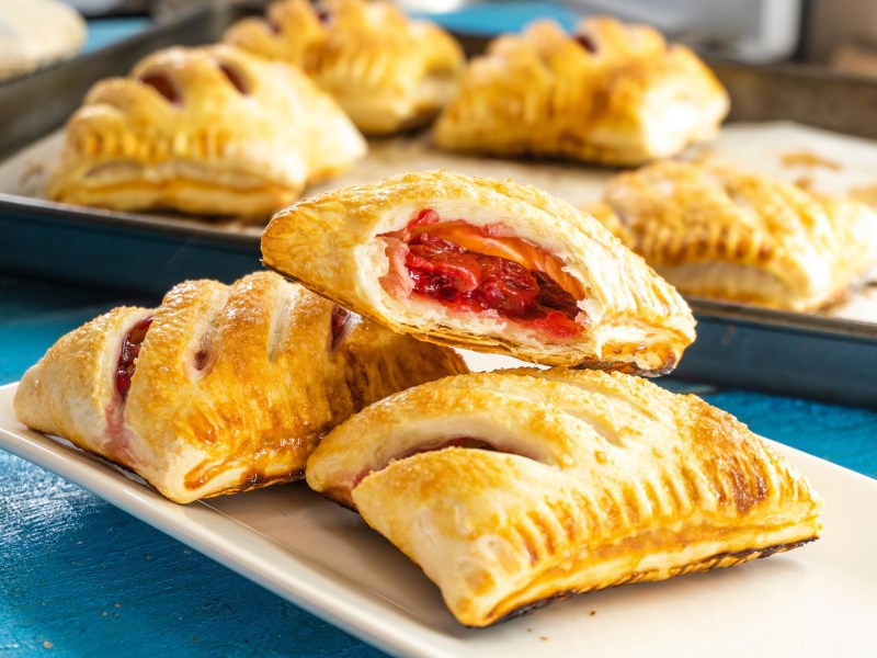 Mehrere Pizzataschen aus BlÃ¤tterteig gefÃ¼llt mit TomatensoÃŸe, GemÃ¼se und KÃ¤se.