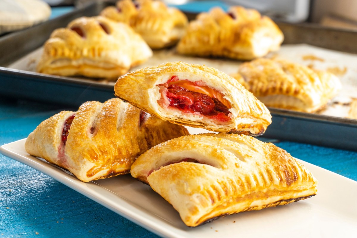 Mehrere Pizzataschen aus BlÃ¤tterteig gefÃ¼llt mit TomatensoÃŸe, GemÃ¼se und KÃ¤se.