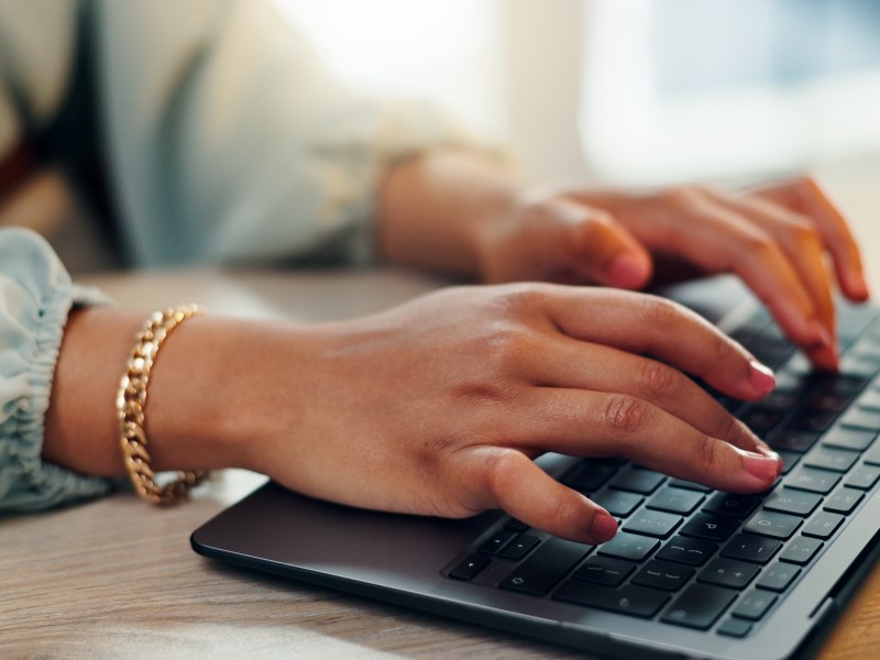 Eine Frau mit roten FingernÃ¤geln tippt auf einer Tastatur.