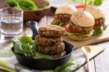 Vegane Bohnen-Burger in einer gusseisernen Pfanne. Dahinter weitere Burger.