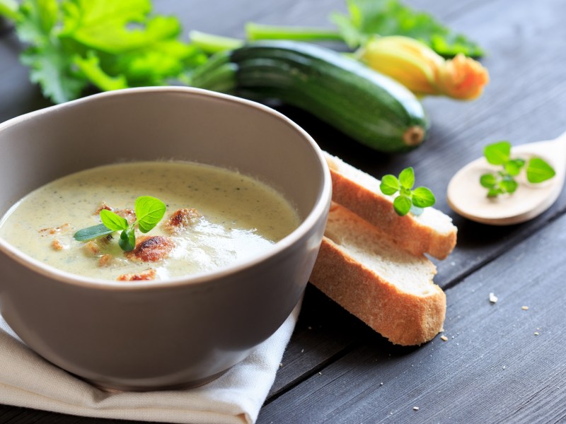 Schale mit Zucchini-Kokos-Suppe und GemÃ¼se daneben