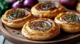 Teller mit Ein leckerer Snack fÃ¼r viele Gelegenheiten: franzÃ¶sische Zwiebel-Tartelettes im handlichen Mini-Format.