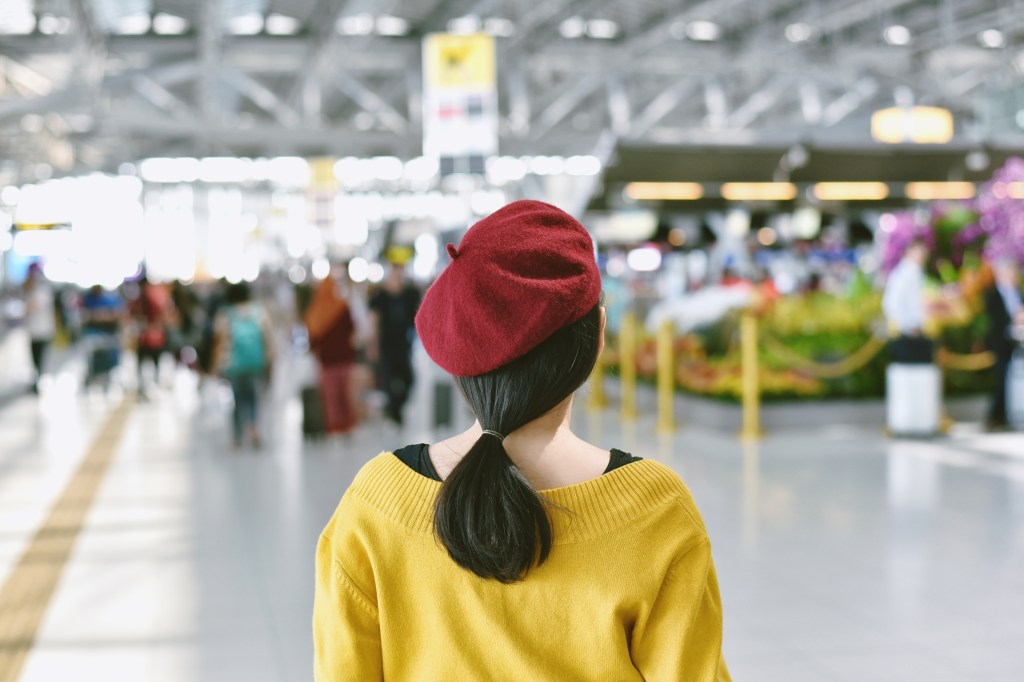 Asiatische Frau steht in der Messehalle, verschwommener Hintergrund einer großen Menschenmenge.